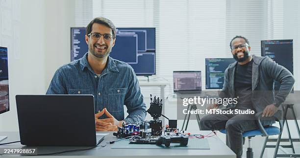 black and hispanic male engineers programmer work together smiling and looking at camera in tech office. software developer technology, artificial intelligence. - java code stock pictures, royalty-free photos & images