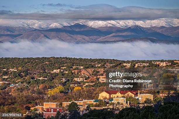 layers of fog and mist over the mountains in santa fe as the morning sunlight lights up houses and trees in a residential area, santa fe, new mexico - santa fe stockfoto's en -beelden