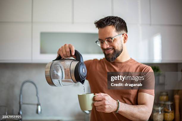 man pouring hot water from kettle into mug - kettle stock pictures, royalty-free photos & images