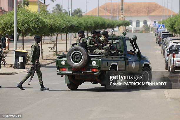 Soldiers hold weapons while patrolling a street near the scene of gunfire near the Presidential Palace in Bissau on November 26, 2025. Gunfire was...