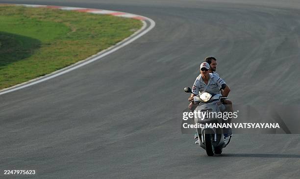Mercedes driver Michael Schumacher of Germany rides a scooter as he inspects the circuit in Greater Noida on October 27, 2011 ahead of the Formula...