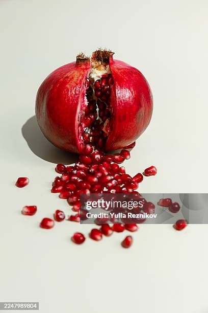 pomegranates and pomegranate seeds on the beige background - pomegranate stock pictures, royalty-free photos & images
