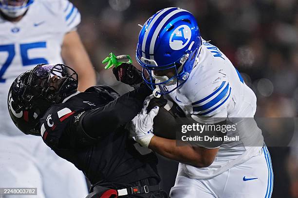 Martin of the BYU Cougars runs with the ball while being tackled by Jiquan Sanks of the Cincinnati Bearcats during the second quarter at Nippert...