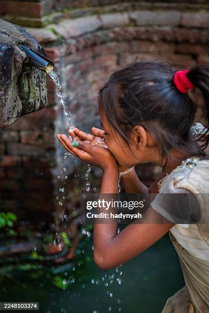 young nepali girl drinking from city fountain on durbar square - nepal people stock pictures, royalty-free photos & images