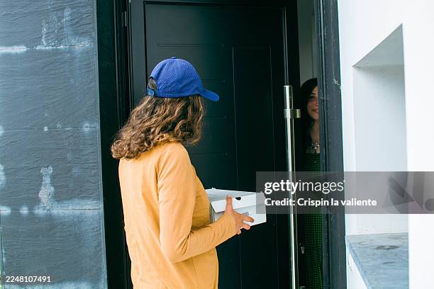 delivery woman giving package to customer at the door - contactless delivery stock pictures, royalty-free photos & images