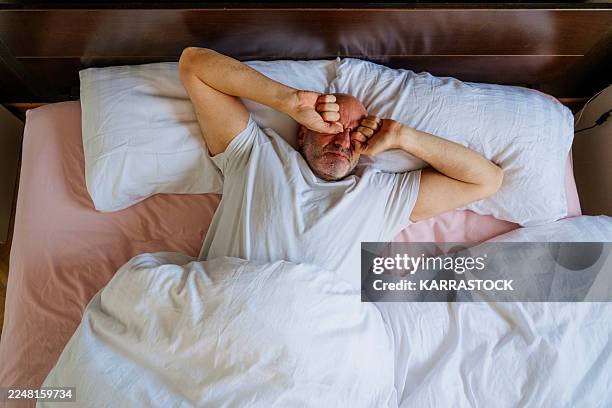 man struggling to wake up in bed - incómodo fotografías e imágenes de stock