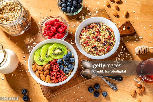overhead view of two bowls of oatmeal and fruits on breakfast table. granola, berry fruits, almonds and honey. snack or meal, healthy eating and dieting concept - trail mix stock pictures, royalty-free photos & images