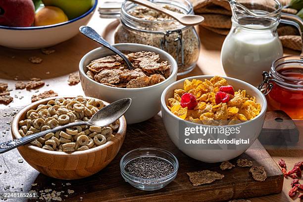 cereali per la colazione sul tavolo della cucina. tre ciotole piene di cereali integrali sani. frutti di bosco, miele, latte e semi di chia, alimenti ricchi di fibre alimentari per il benessere e il benessere del sistema digerente e dell'intestino - cereali da colazione foto e immagini stock