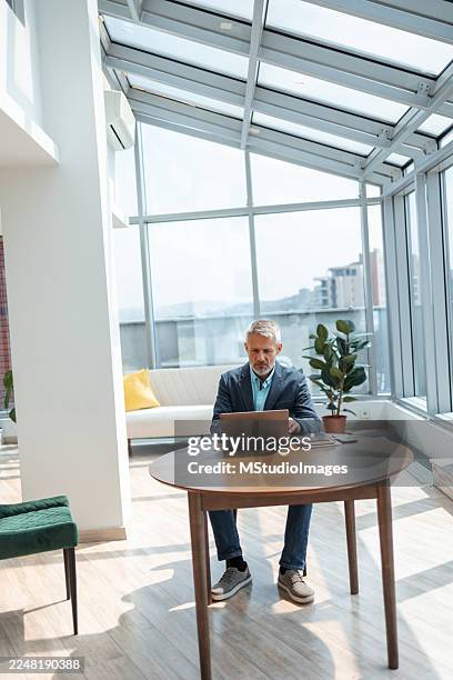 hombre profesional trabajando en un portátil en una oficina moderna y luminosa - vida sencilla fotografías e imágenes de stock