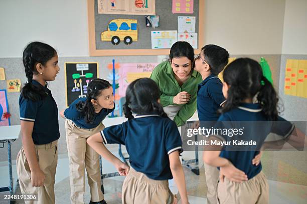 teacher leading fun whisper game with young students in classroom - role play stock pictures, royalty-free photos & images
