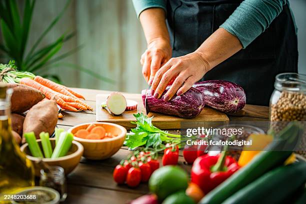 persona irriconoscibile che affetta melanzane fresche biologiche, chef che prepara un pasto vegetariano sano sul tavolo della cucina, taglia verdure. mangiare o fare dieta sana - melanzana foto e immagini stock