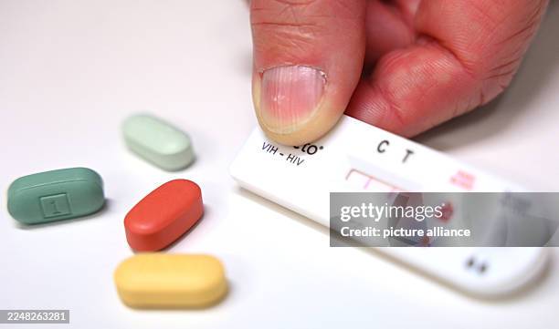 November 2025, Berlin: A man holds a rapid HIV test with a positive result in his hand in the offices of Berliner Aids-Hilfe e. V.. Next to it are...