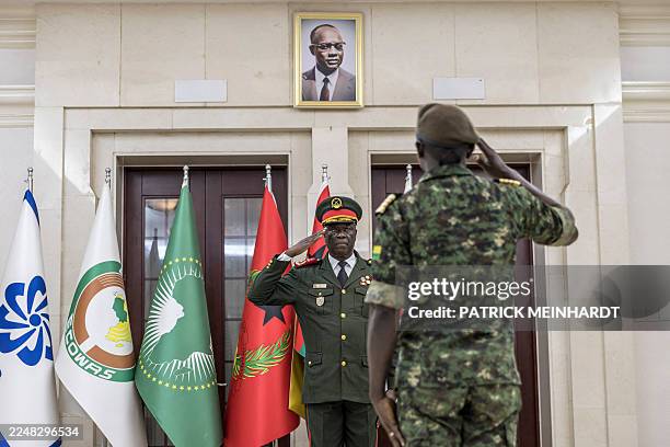 Transitional government President General Horta N'Tam salutes an army officer next to a portrait of freedom fighter and founder of the African Party...
