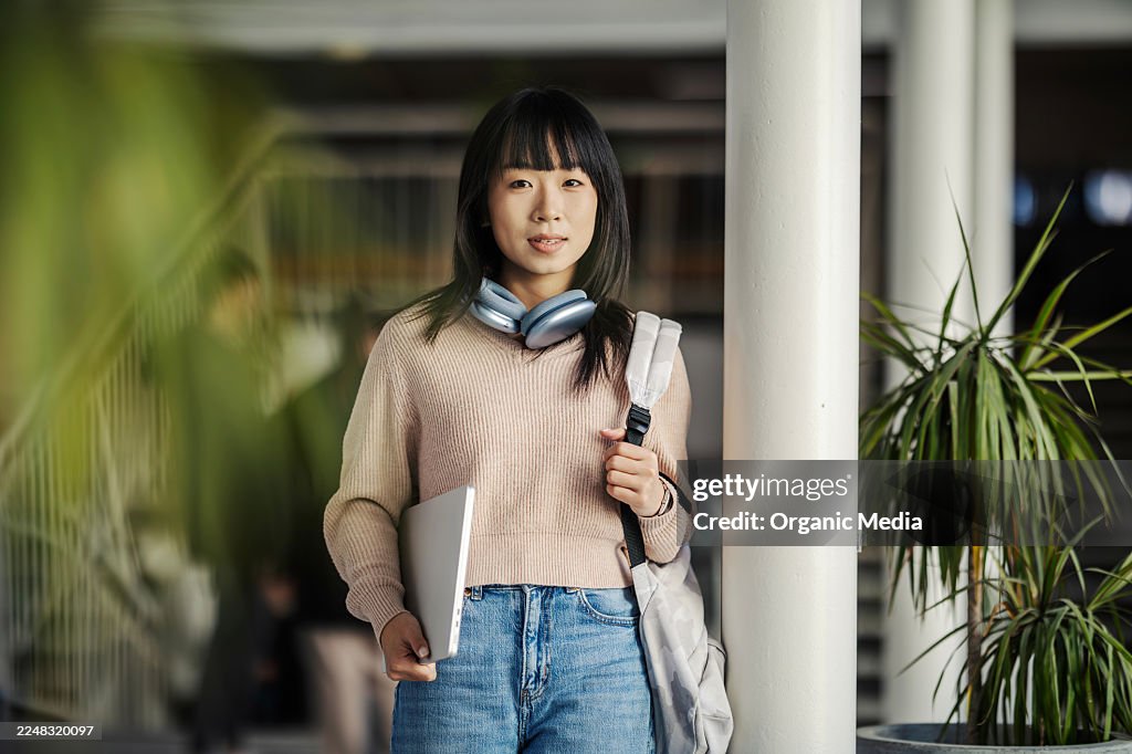 Young asian woman student carrying backpack and laptop