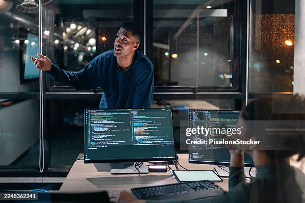 two computer programmers working together on a computer code at night. - web designer fotografías e imágenes de stock
