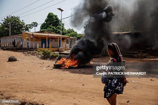 Woman approaches burning tyres in the area of incidents between security forces and protestors in Bissau on Novmeber 29, 2025.