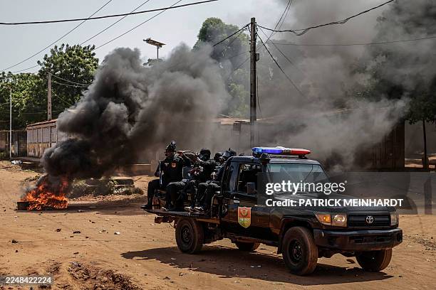 Guinea Bissau security forces patrol car drives near burning tyres in the area of incidents with protestors in Bissau on Novmeber 29, 2025.