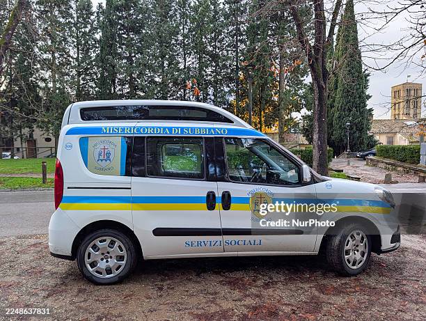 White van belonging to Misericordia di Subbiano, marked with the words ''SERVIZI SOCIALI'' and blue and yellow stripes, parks on a dirt road next to...