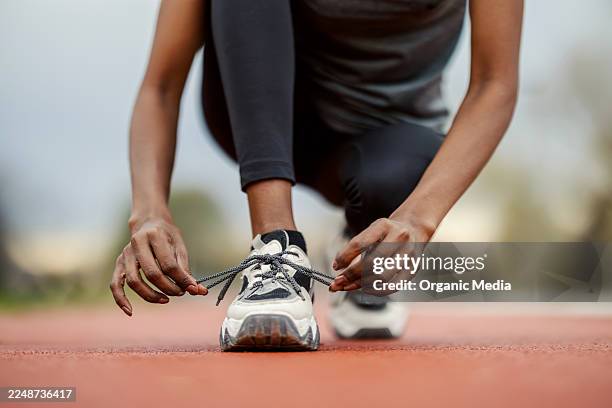 black woman tying running shoe on track preparing for workout - sporting footwear stock pictures, royalty-free photos & images