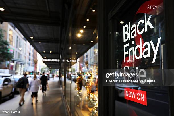 Pedestrians and shoppers move past David Jones Store shop windows during a Black Friday sale on November 28, 2025 in Sydney, Australia. Australians...