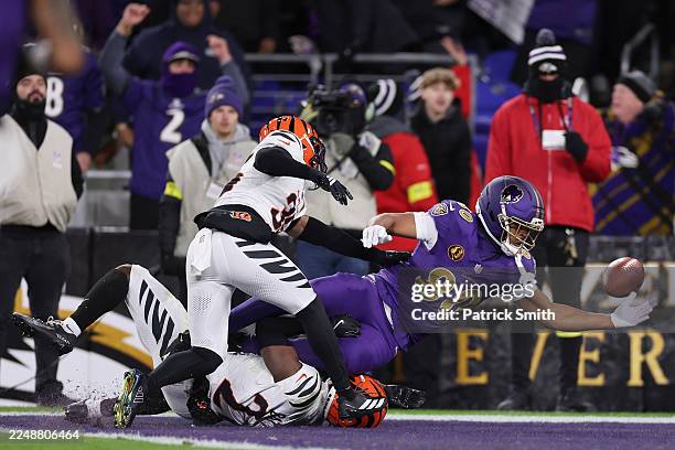 Isaiah Likely of the Baltimore Ravens fumbles the ball defended by Jordan Battle and Jalen Davis of the Cincinnati Bengals during the second quarter...