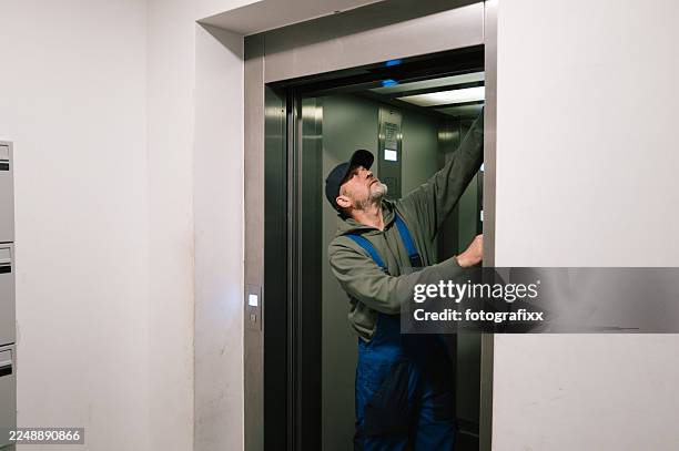 maintenance engineer examining elevator doors in an apartment building - concierge stockfoto's en -beelden