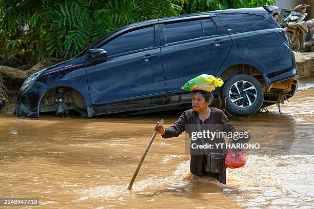 Woman wades through the floodwater in the aftermath of flash floods at Tukka village, Central Tapanuli, North Sumatra province, on December 2, 2025....