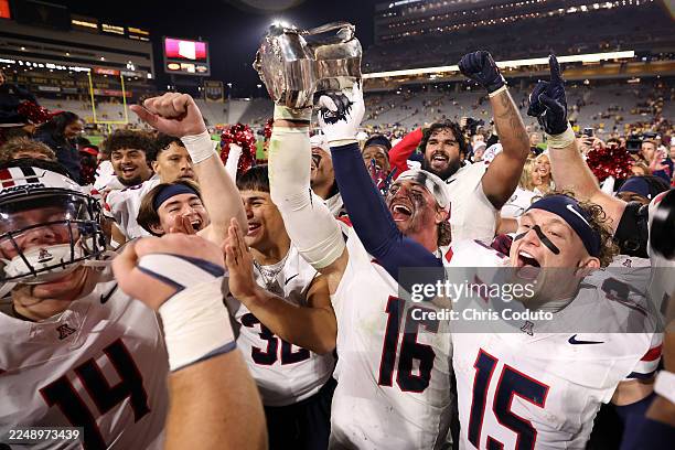 Linebacker Riley Wilson and wide receiver Luke Wysong of the Arizona Wildcats celebrate with the Territorial Cup after defeating the Arizona State...
