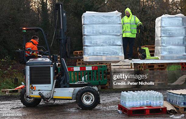 Volunteers from South-East Water assist members of the public load bottled water into their vehicles at a distribution point on December 2, 2025 in...