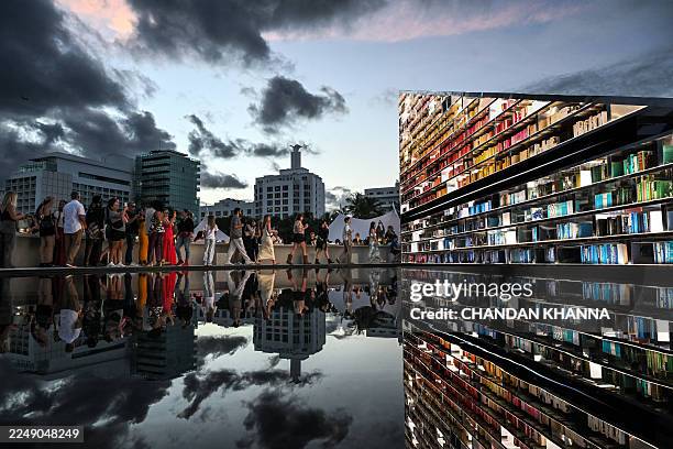 People look at the exhibition "LIBRARY OF US" by British artist Es Devlin, a 50-foot-wide rotating triangular bookshelf containing 2,500 books that...
