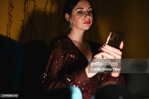 frau im paillettenkleid benutzt nachts smartphone - paillettenkleid stock-fotos und bilder
