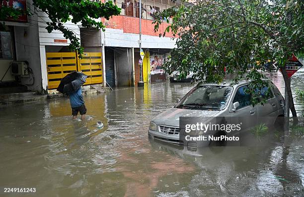 Man walks through a waterlogged street after heavy rains triggered by Cyclone Ditwah in Chennai, India, on December 3, 2025.