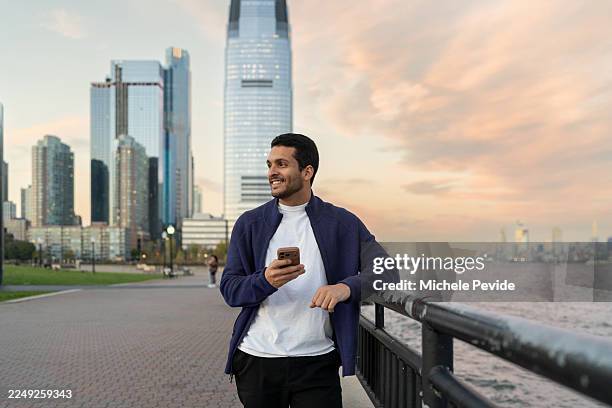 latin man using mobile phone outdoors - liberty state park stock pictures, royalty-free photos & images