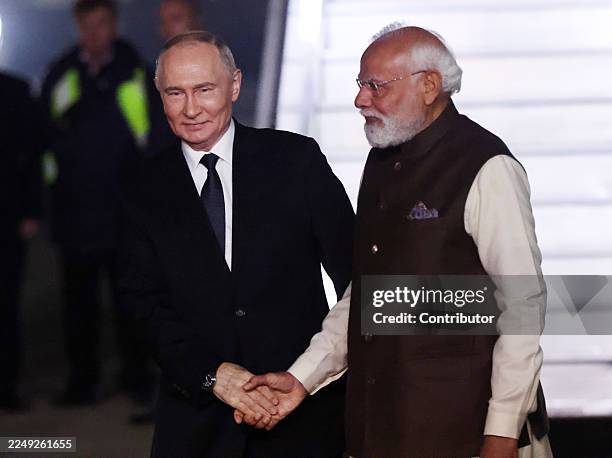 Russian President Vladimir Putin shakes hands with Indian Prime Minister Narendra Modi during his arrival at the airport, on December 4, 2025 in New...