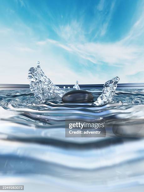 water splash caused by a stone dropping into a calm lake creating ripples and reflections under a bright sky - pebble stock pictures, royalty-free photos & images