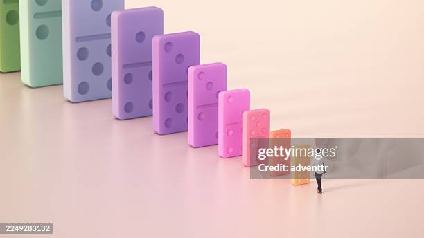 colorful dominos create a visual path leading to a figure in a bright, minimalistic setting. leadership concept - domino effect stock pictures, royalty-free photos & images