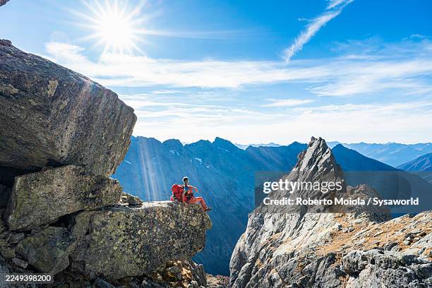 hiker sitting on rocks admiring mountains - ein mann allein stock-fotos und bilder