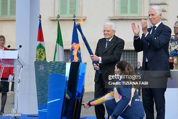 Italy's President Sergio Mattarella lights a cauldron with a torch next to President of the Milano Cortina 2026 Organizing Committee Giovanni Malago...