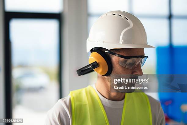 construction worker in safety gear at a new office site, wearing helmet and ear protection - ear defenders stock pictures, royalty-free photos & images
