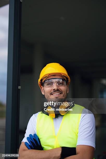 confident construction worker in high-visibility vest and safety gear at office build entrance - ear defenders stock pictures, royalty-free photos & images