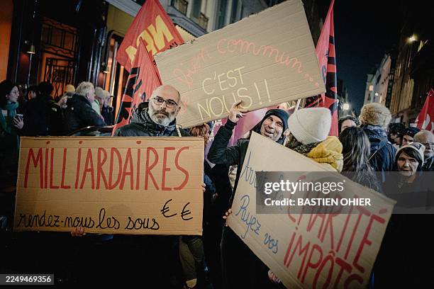 People are holding signs that read Milliardaires rendez nous les sous Le bien commun c est nous and Arretez la charite payez vos impots during a...