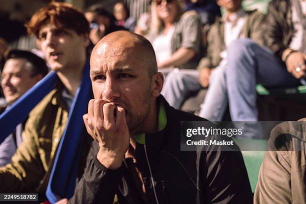 concentrated bald man biting nails while watching game from stadium stand - nail biting stock pictures, royalty-free photos & images