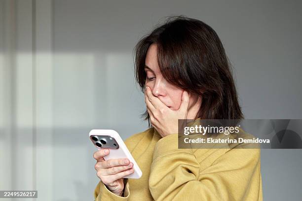 woman receiving shocking news on smartphone looking surprised - shocked woman stock pictures, royalty-free photos & images