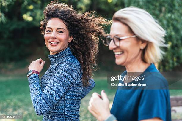la joie à chaque pas. deux amies qui courent dans le parc. - marche sportive photos et images de collection