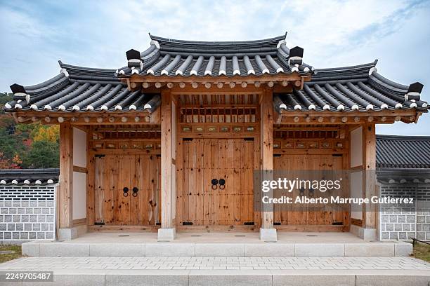 tradizionale cancello coreano in legno hanok con tetto in tegole e muro in pietra, ingresso architettonico storico che mette in mostra maestria artigianale e patrimonio - tradizione foto e immagini stock