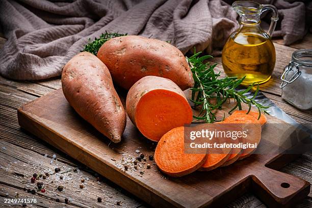 batatas enteras y rodajas crudas sobre la mesa de la cocina. vegetal de raíz o alimento rico en carotenoides dietéticos, polisacáridos y carbohidratos, antioxidantes y antiinflamatorios - boniato fotografías e imágenes de stock