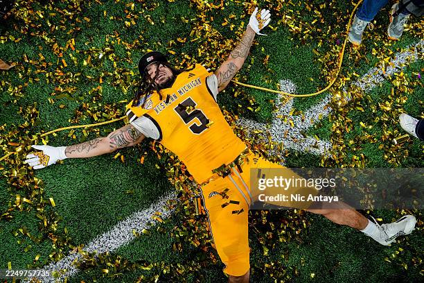 Devin Miles of the Western Michigan Broncos makes a snow angel in confetti after the Western Michigan Broncos won the 2025 MAC Football Championship...