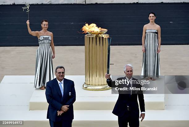 Giovanni Malago, President of the Milano Cortina 2026 Organizing Committee, holds the Olympic Flame following the handover from Isidoros Kouvelos,...