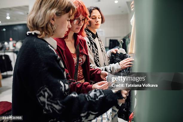 friends shop for clothes in a bright fashion store, browsing shirts and jackets - fast fashion stock pictures, royalty-free photos & images
