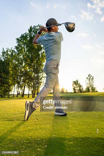 caucasian man in mid-adulthood enjoying golf swing at sunset on course - teeing off stock pictures, royalty-free photos & images
